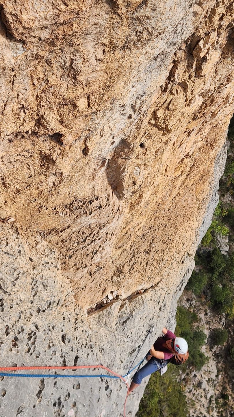 Une grimpeuse au pied du rocher orangé à Aiglun