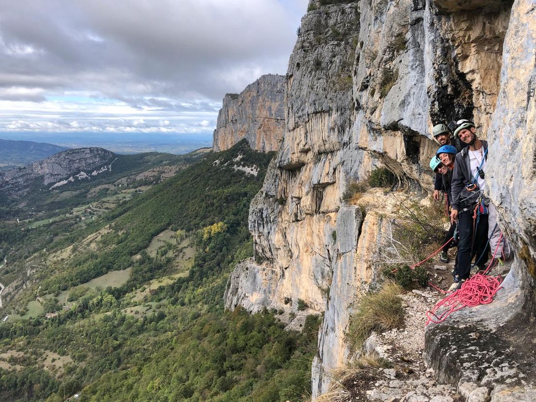 Une cordée sur une vire au pied de la paroi, au-dessus de la vallée