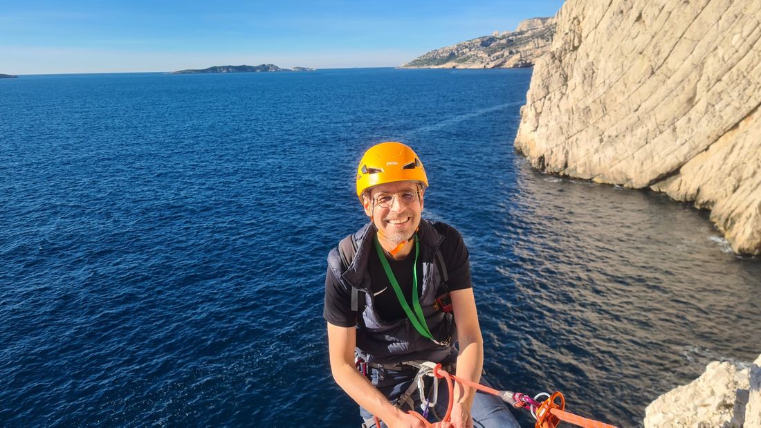 Un grimpeur au relais au-dessus de la mer dans les Calanques